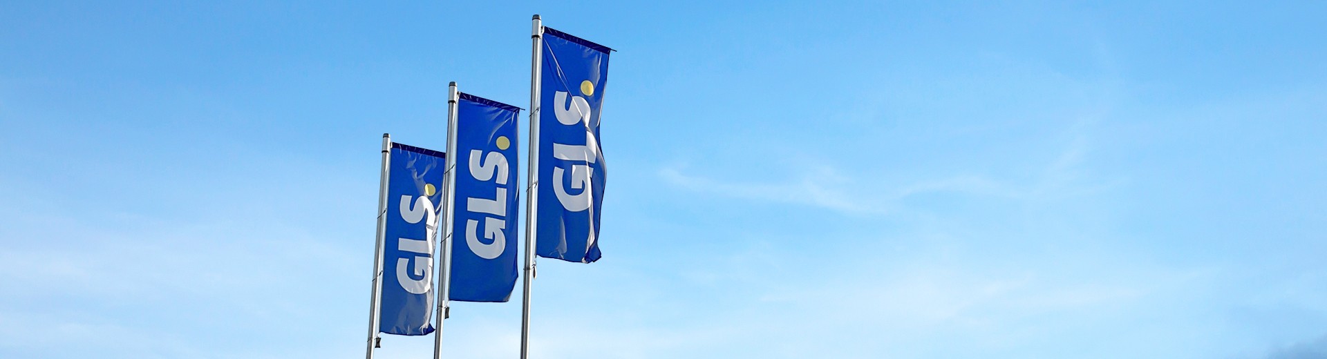 Drapeaux bleus GLS flottant devant un ciel bleu, symbolisant le transport et la logistique de colis en Europe.