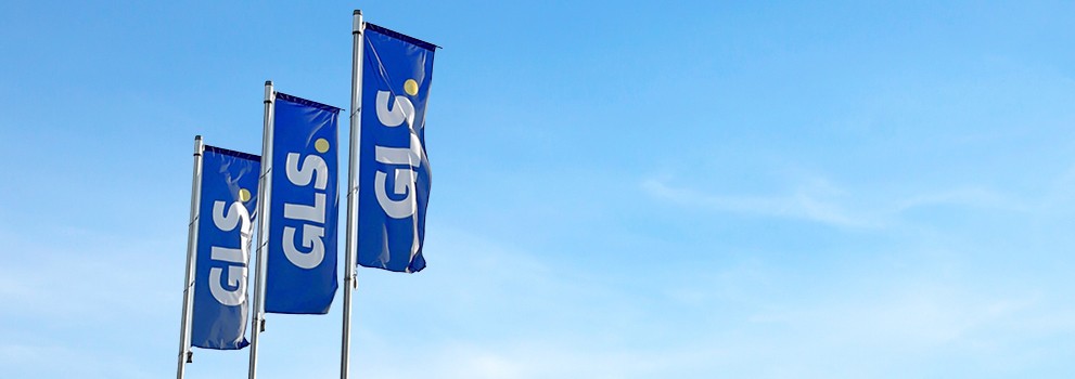 Drapeaux bleus GLS flottant devant un ciel bleu, symbolisant le transport et la logistique de colis en Europe.
